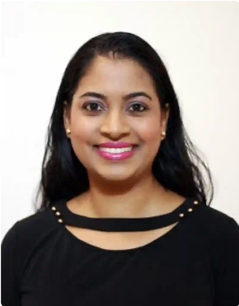A smiling woman with long black hair, wearing a black top with a golden accent, and a bright pink lipstick, posing for the camera.